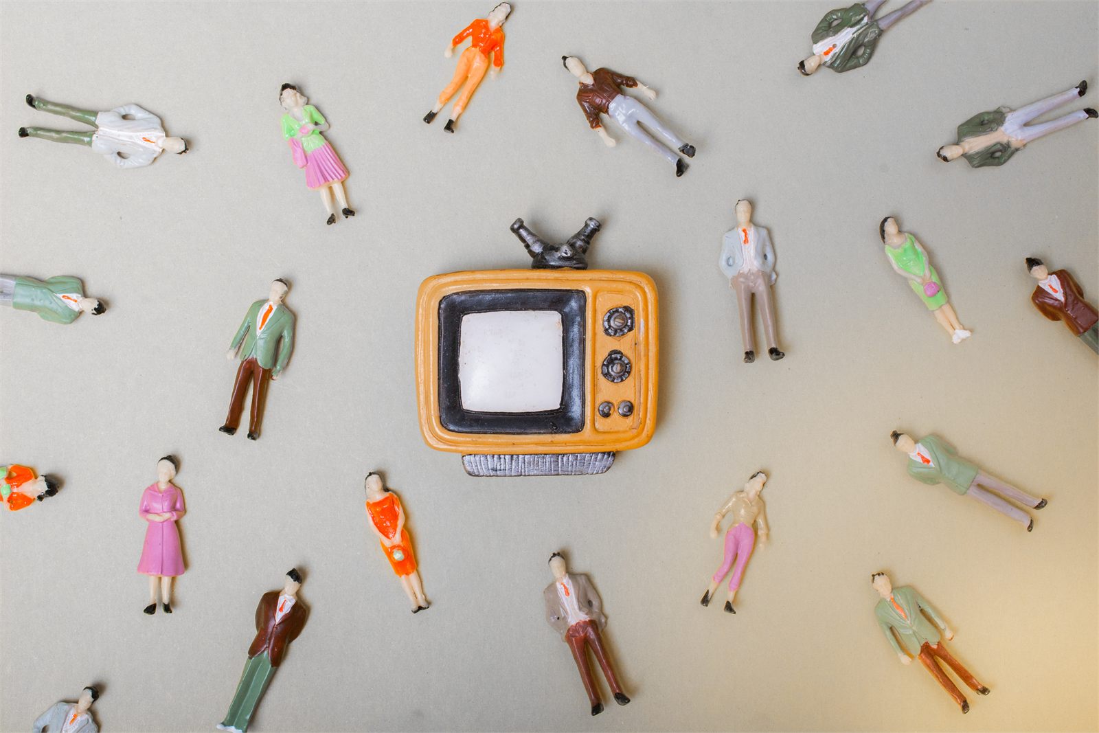 Miniature people gathered around a retro television, suggesting how people watch, interpret and respond to one another.
